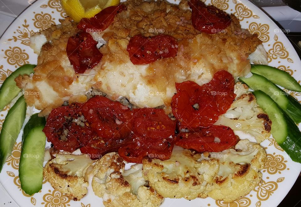 Oven baked haddock, with roasted beefsteak tomato slices with cauliflower and lemon.