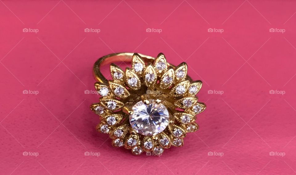 Gold  finger ring with quartz rock crystal Stone placement background pink 