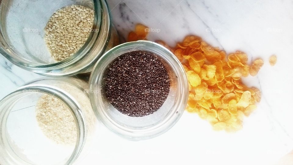 corn cereal on white marble with different seeds in mason jars