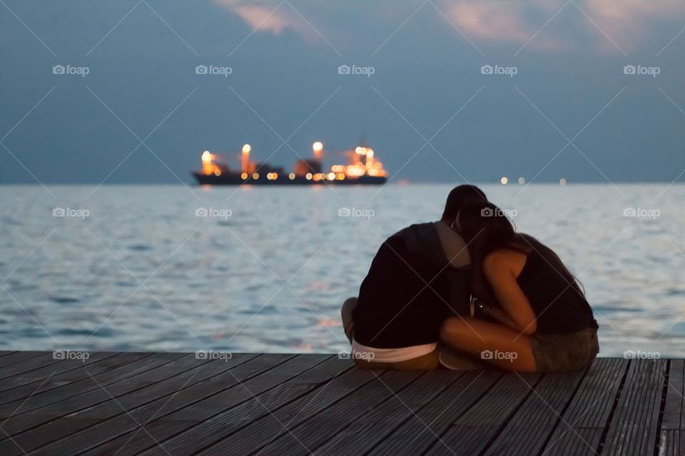 Couple In Love Sitting At The Dock Talking And Enjoying The Night View
