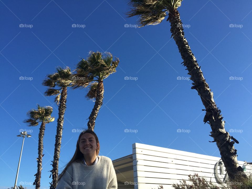 Woman smiling against palm trees with blue sky