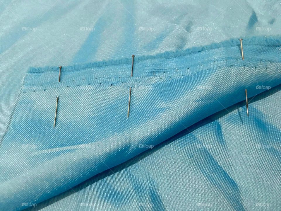 Baby blue satin fabric with sewing pins