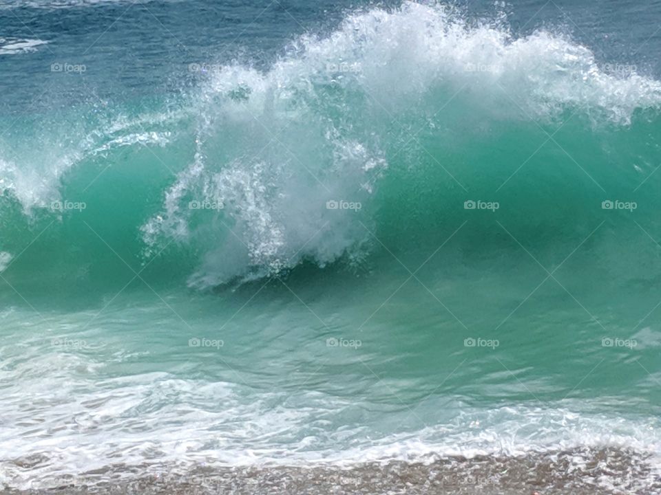 Wave cresting and Sea Foam white contrasting against turquoise blue water.