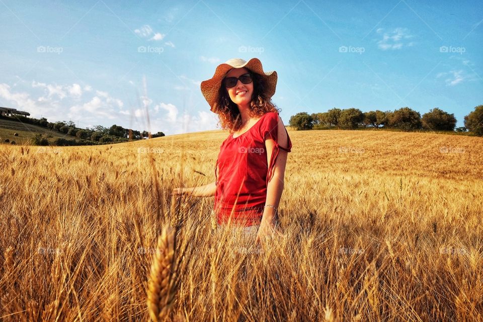 Woman with straw hat in a ripe wheat field