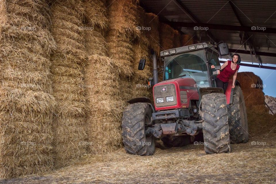 Girl on a tractor near hey stacks