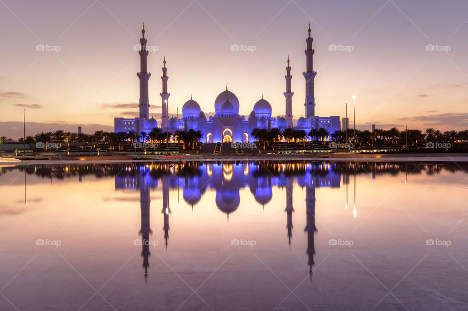 Sheikh Zayed Grand Mosque in Abu Dhabi during the sunset reflecting in the lake