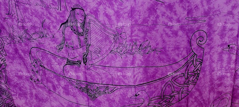 A “Gaelic” motif of a lady playing the harp traveling the waters in a gondola adorns marbleized fabric in the most striking shade of purple. It is part of the decor for an evening of “Irish Folklore” held in “Bavaria” in 2023. Hypnotic Productions