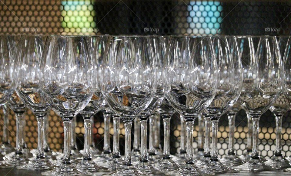 Wine goblets, sparkling clear crystal glass red wine glasses on shelf with red and yellow lighted background, concept celebration, winery, wine tasting, catering, event, restaurant, holidays, gourmet,