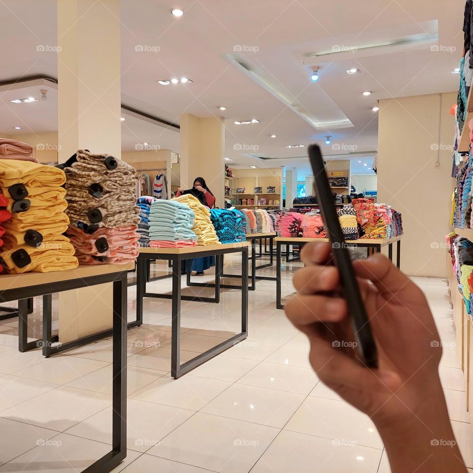 waiting for clothes shopping while playing cellphone