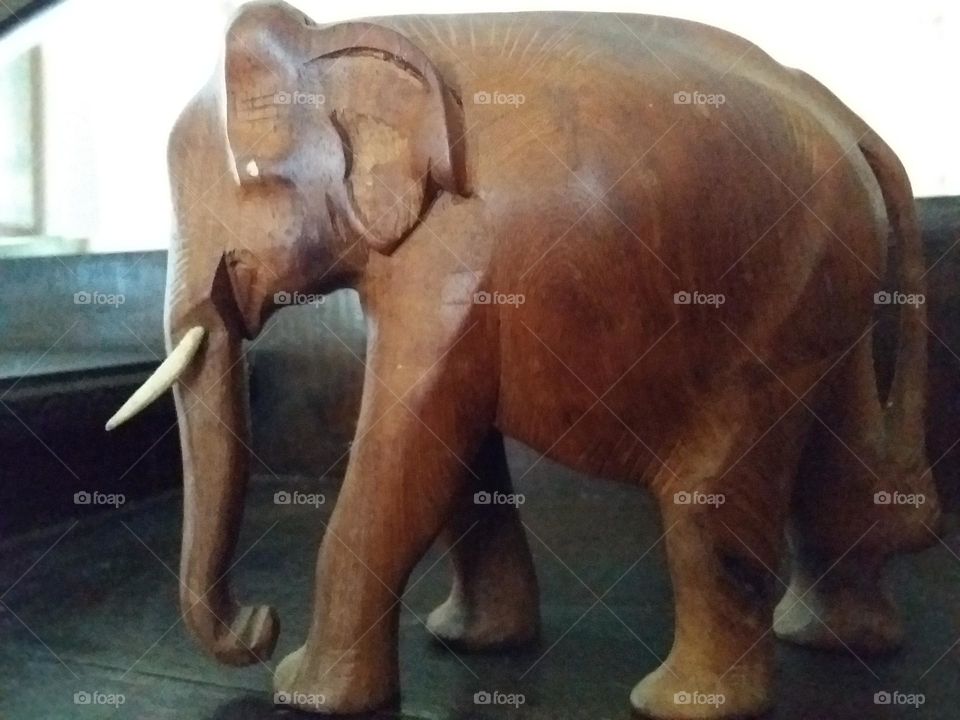 a carved wooden elephant standing on an antique wooden sideboard