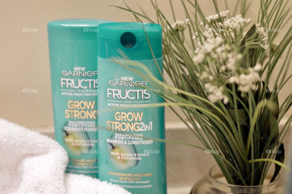 Garnier shampoo and conditioner on the bathroom counter top with a white towel and a plant in the background