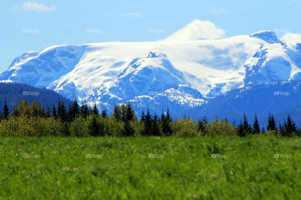 Snow stays on this glacier and in the mountains until mid-summer but Spring begins the melt by sending the sun and warm air rushing across the verdant farm fields to meet and defeat Winter. 