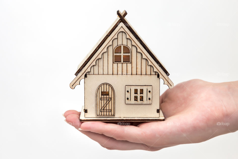 ,a girl holding a toy house in the hand on a white background