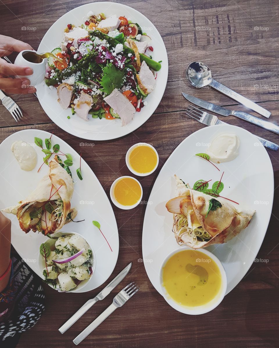 Three plates containing soup, salad and fresh wraps. Comfort food in flatly setting