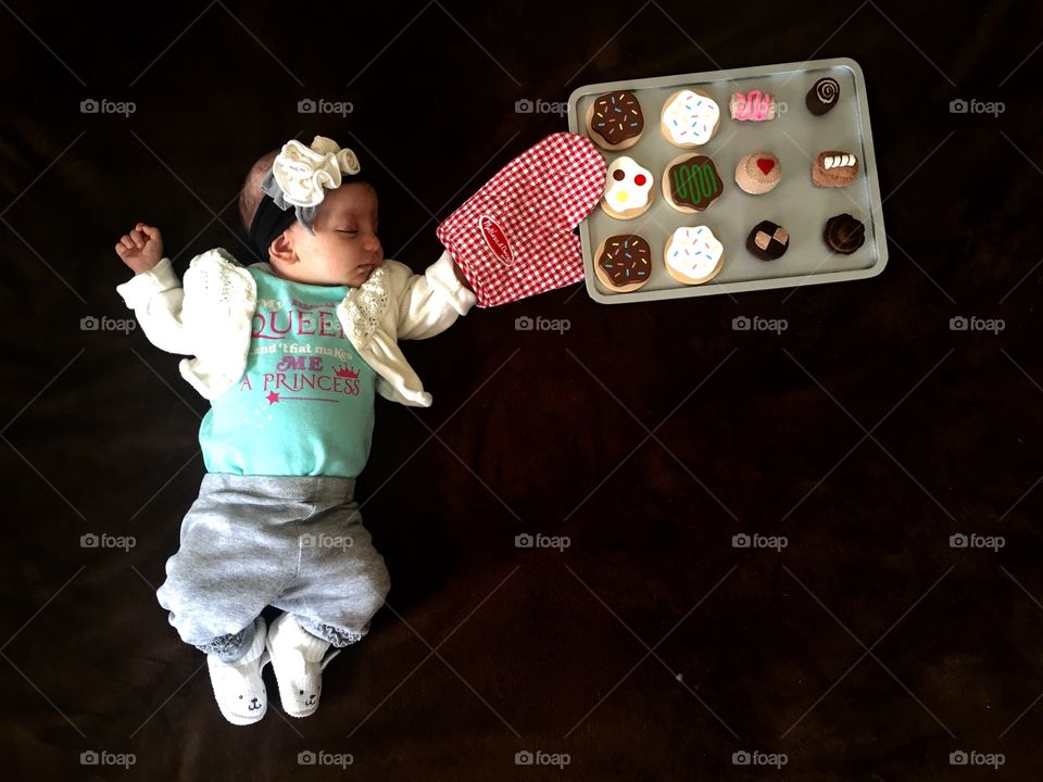 Baby lying on bed with fake baking tray