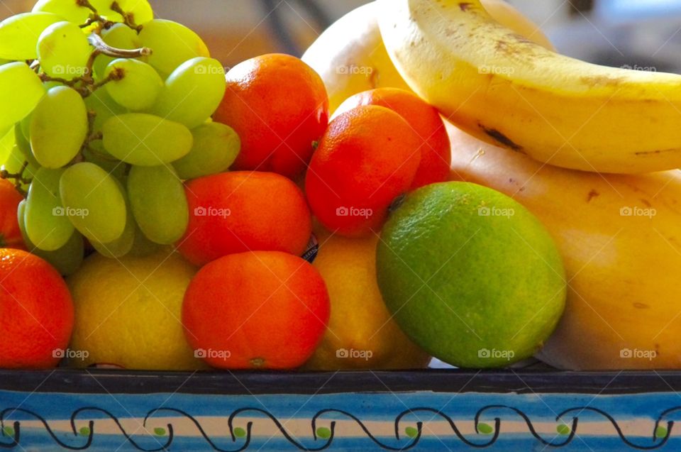 Interior.  Prince Albert, PA, SK.  Closeup.  A still life of fruit (grapes, tangerines, limes, bananas and lemons) on a platter 