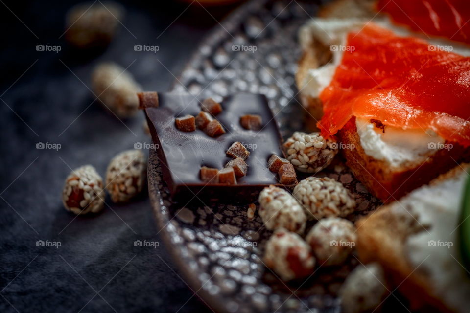 Dark chocolate and nuts on plate with sandwich 