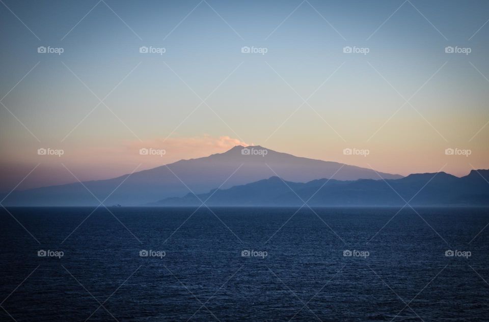 Mount Vesuvius is silhouetted against the dusky sky as it quietly smokes