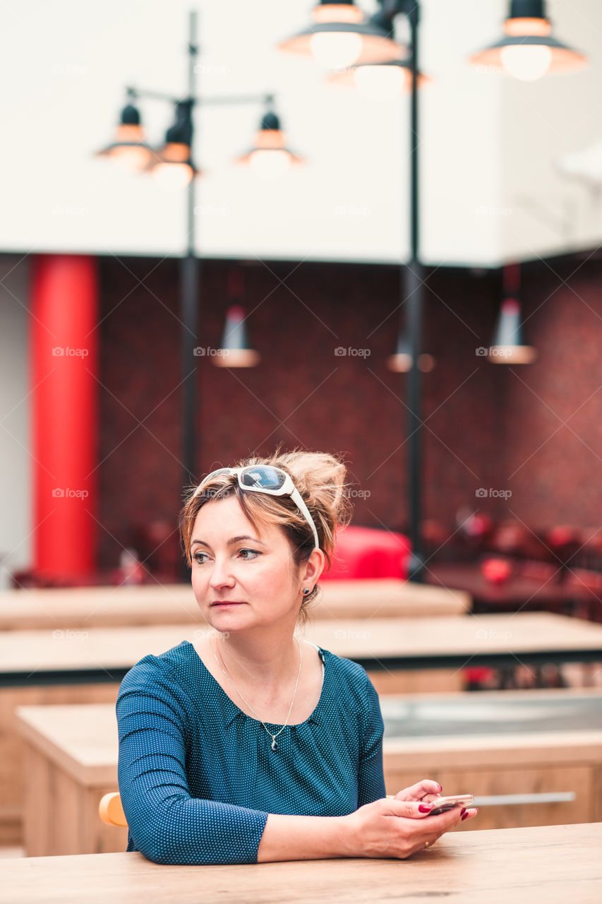 Young woman using mobile phone sitting by a table in cafe