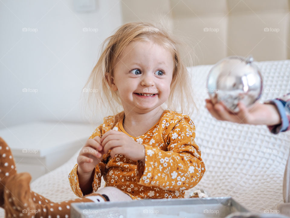Funny blond toddler girl smiling with Christmas ball
