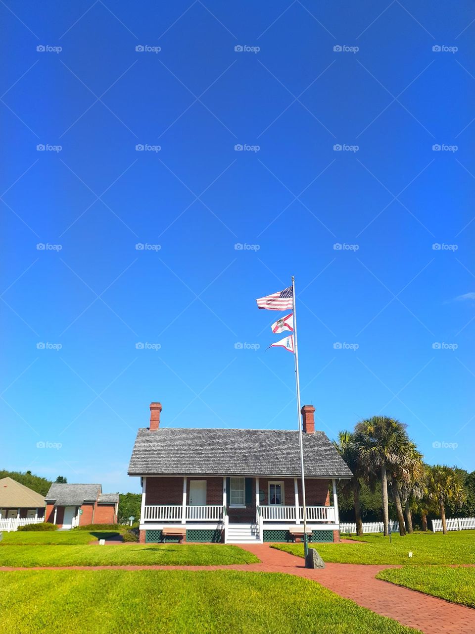 Photo of a house that is part of the museum in Ponce Inlet, Florida. There is a flag pole out front with an American flag on it.
