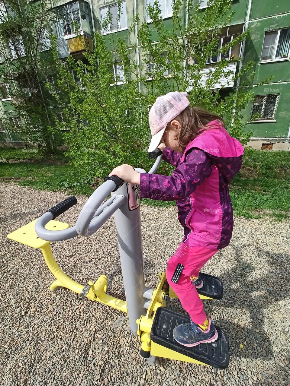 sports, fitness equipment, training on the street, a child and exercise equipment, a walk, playing sports, a girl in a jacket, a green house, a city, a girl goes in for sports.