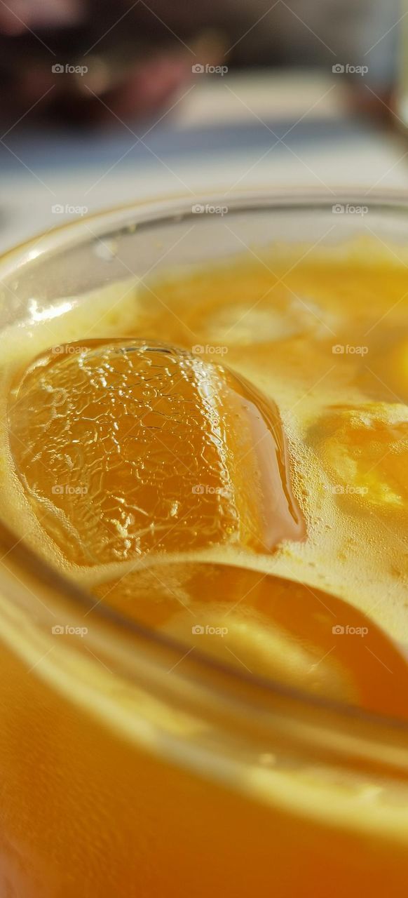 Close up of ice cube in an orange juice glass