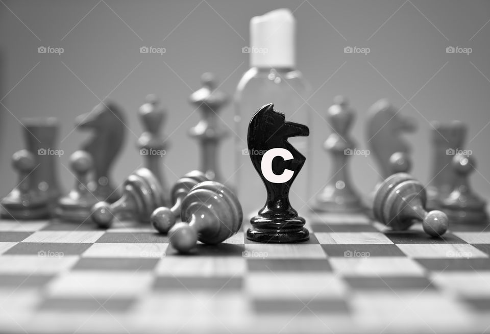 Coronavirus concept image chess pieces and hand sanitizer on chessboard illustrating global struggle against novel covid-19 outbreak.