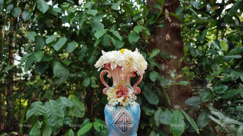 Beautiful white flowers in a colourful flowerpot with a flower sculpture, Flowers in a vase, colourful vase, white flowers in a vase