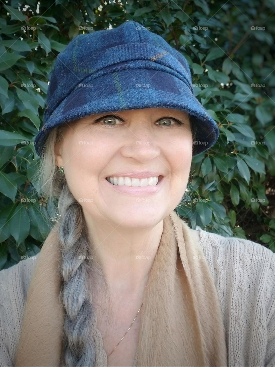 Be Authentic Demi Saison: Me, A smiling woman in a wool cap, scarf & light sweater on a crisp morning by the Photinia bushes