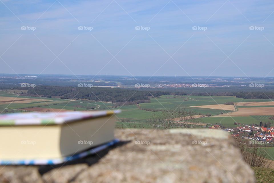 Close-up of a book on a rock with a landscape in the foreground