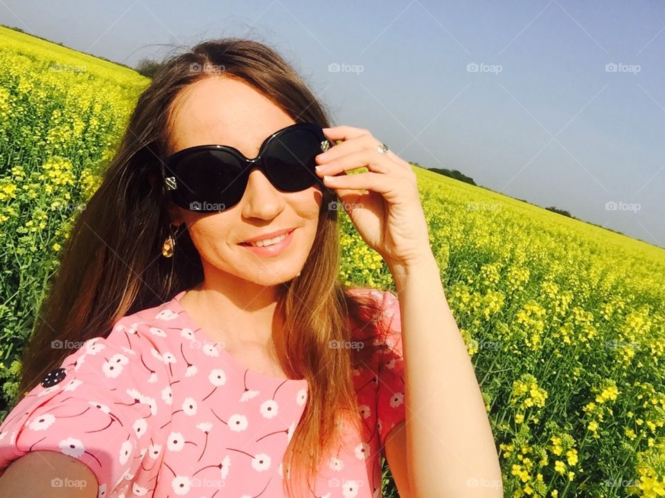 Portrait of smiling woman wearing sunglasses in canola field