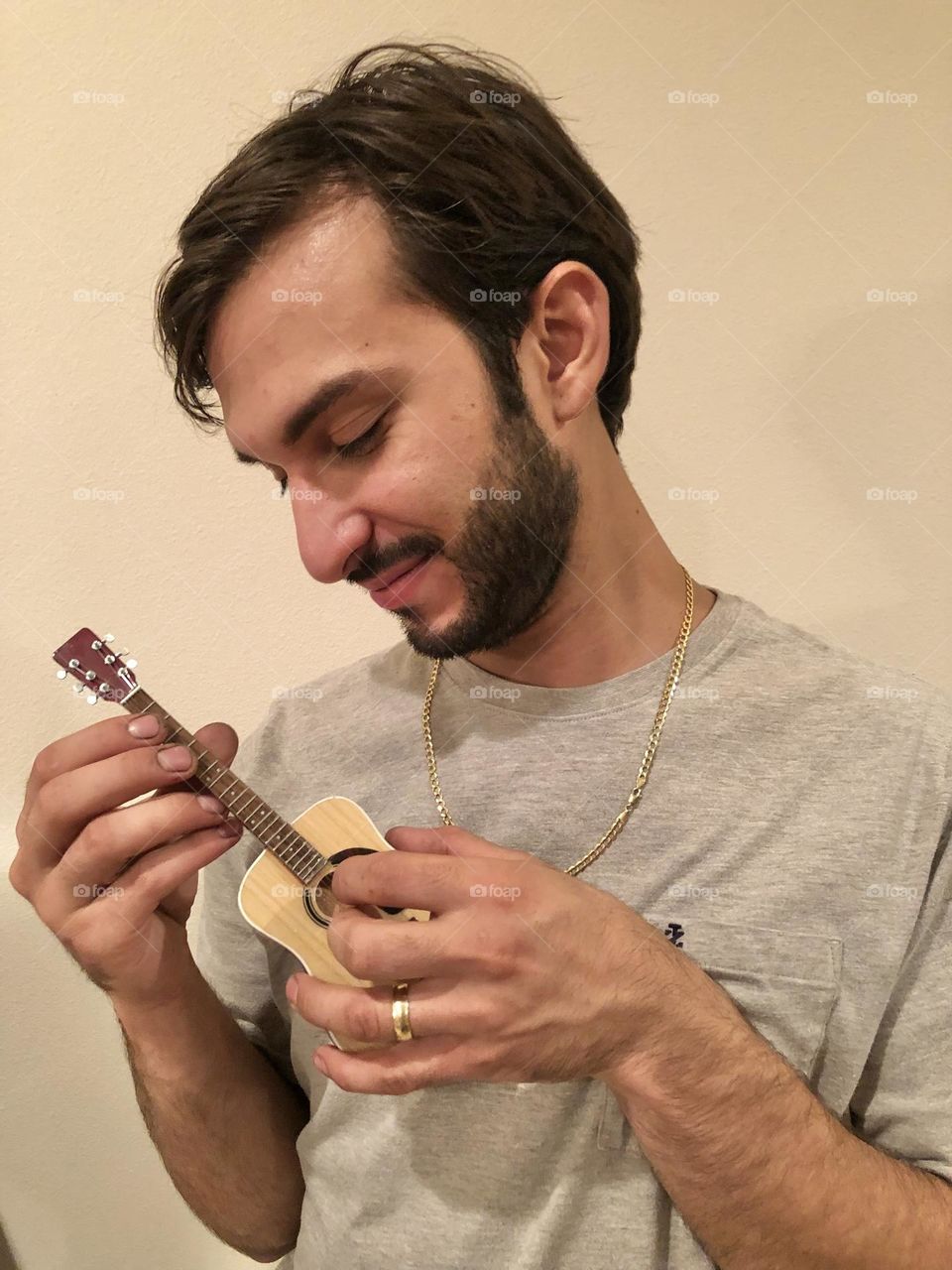 Profile of young bearded man showcasing decorative mini guitar