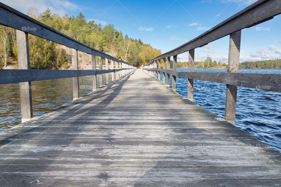 Long wooden bridge made for walking and hiking leading across the lake on a beautiful sunny day 