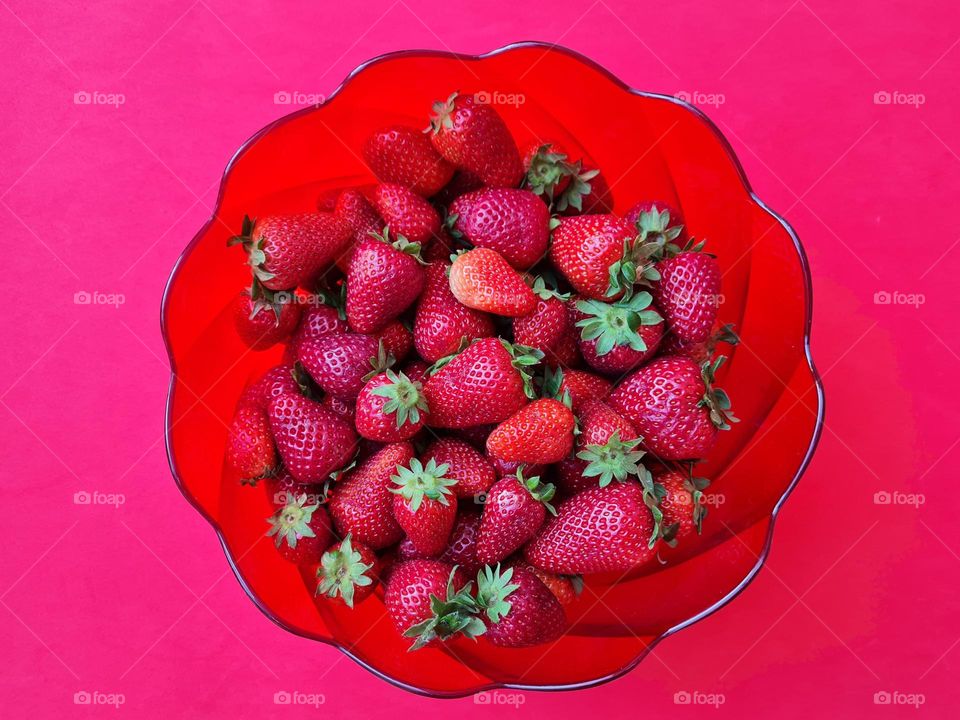 red bowl with strawberries on red background