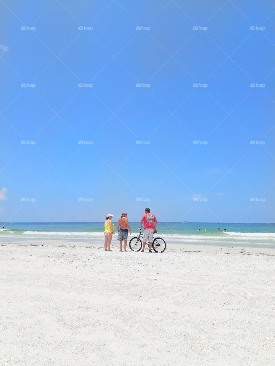 Three friends share a conversation while enjoying the day at Indian Rocks Beach in Tampa, Florida.