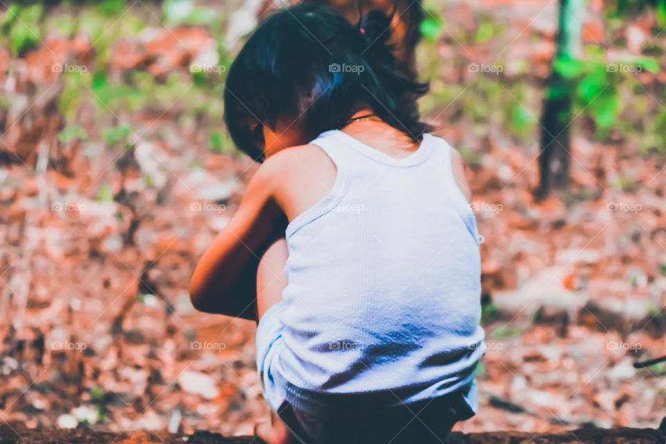 child sitting in the middle of the forest