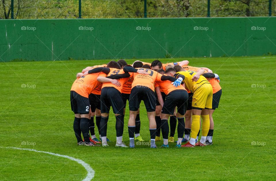 Professional football players huddled in circle for a team pep talk before a soccer match