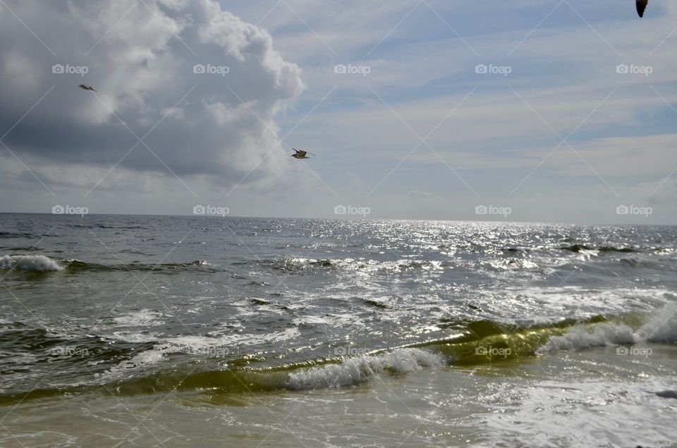 storm clouds, rough Seas, partially clear skies with seagull in flight at the beach