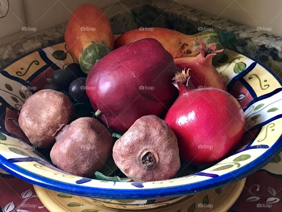 A pottery bowl of small potatoes and red onions 