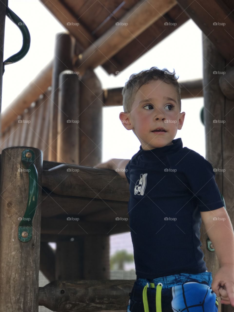Portrait of a boy standing near wooden post looking away