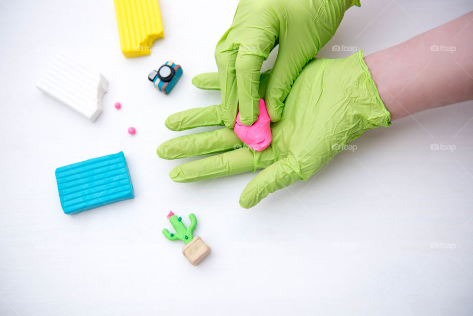 Tiny clay objects and a person's hands molding colorful clay