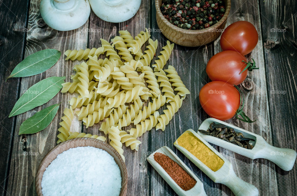 Raw pasta with ingredients and wooden accessories