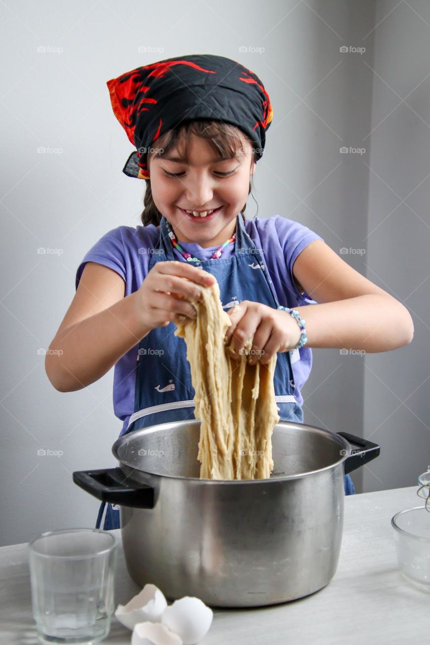 Happy little girl is helping with a bread dough