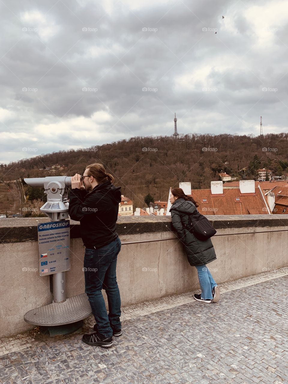 A photo of Prague with a person looking in binoculars. 