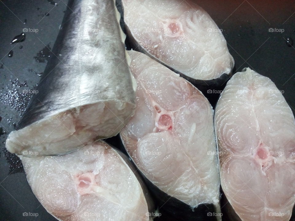 Raw silver fish cuts on a black pan