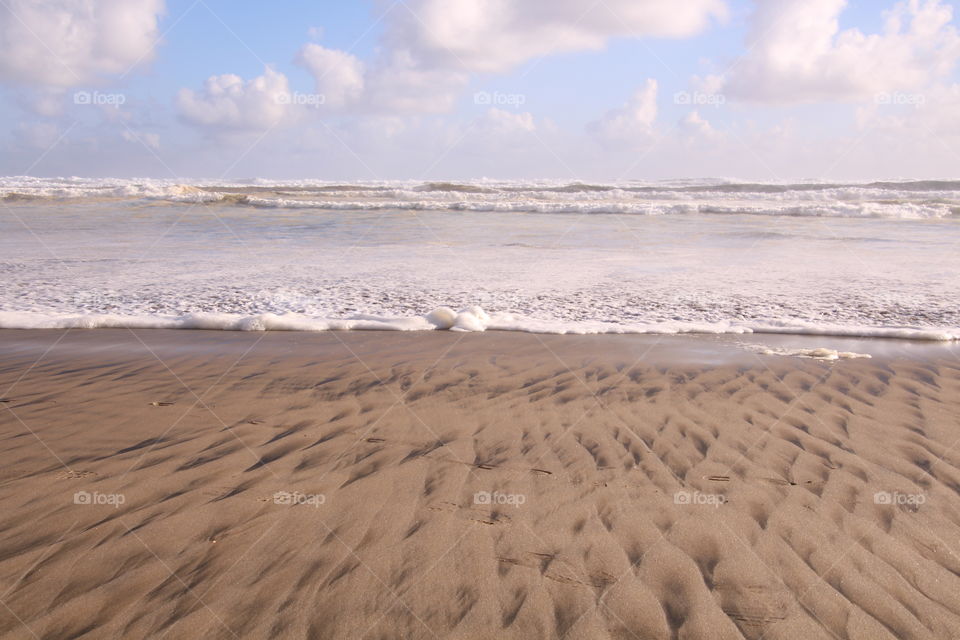 iron making patterns in the sand with waves lapping the shore