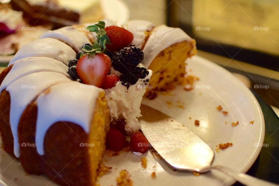 Beautiful Bundt cake topped with fruit and icing on a plate