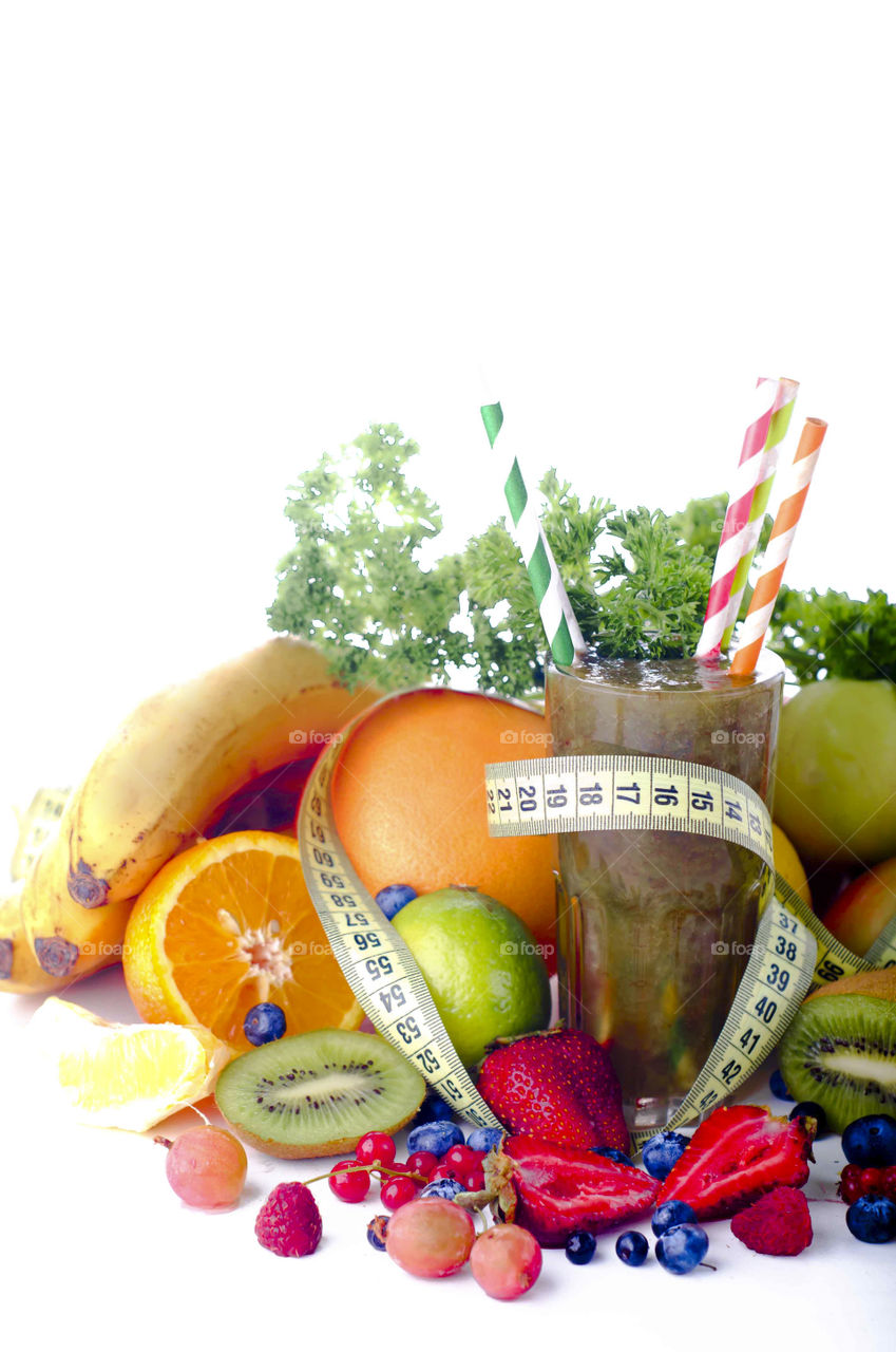 View of smoothie in glass between fresh fruits