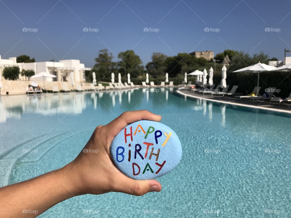 Happy Birthday stone front of a swimming pool 